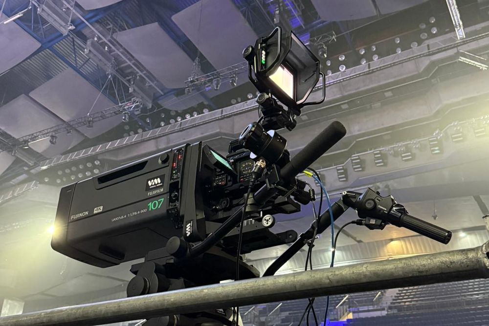 Cámara broadcast con óptica de largo alcance siguiendo una competición deportiva