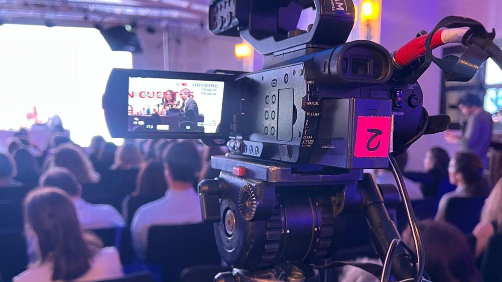 Cámara grabando una mesa redonda durante un congreso con público en sala